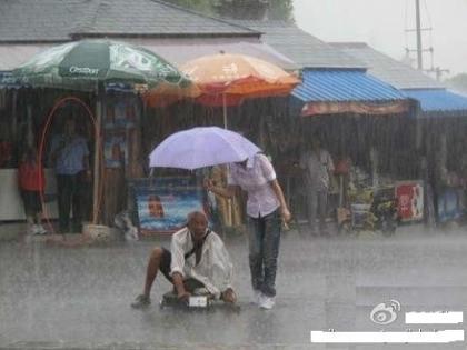 因腿部残疾而只能靠讨饭维生的大爷来不及避雨，只能望雨兴叹。突然，老人的头上多了一把雨伞。老人疑惑着抬起头，却看到了一位美丽的姑娘，雨伞已经完全偏向于老人，自己上衣、牛仔裤、运动鞋却完全湿透。而另一名制服男，却在棚下避雨，远远观望.jpg